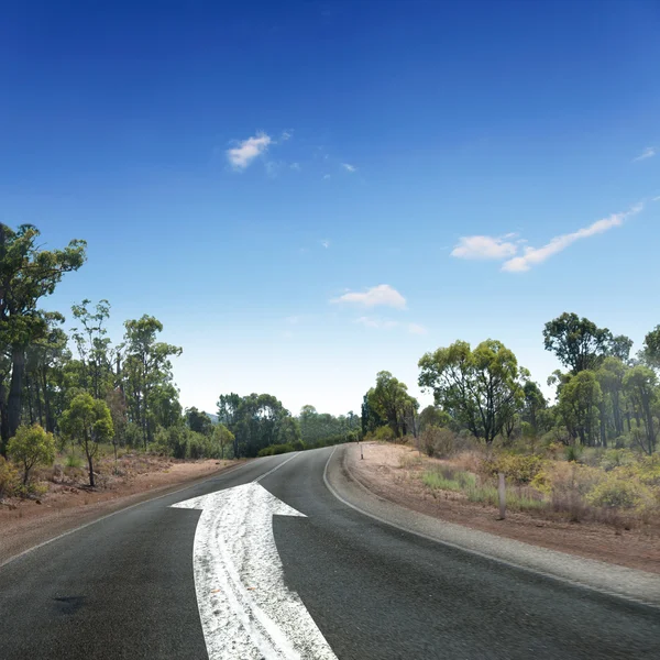 白い矢印の付いた空の田舎道 — ストック写真