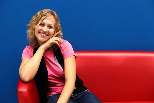 Ung kvinna sitter på röd soffa — Stockfoto