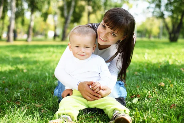 Jovem mãe com seu filho no parque de verão — Fotografia de Stock