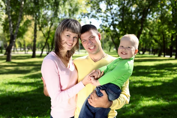 Młode rodziny z dzieckiem w lato park — Zdjęcie stockowe