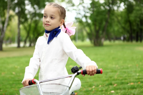 女孩骑着自行车在绿色公园 免版税图库照片