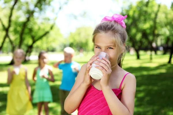 Flicka konsumtionsmjölk i parken sommaren — Stockfoto