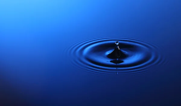 Droppe vatten faller i vattnet — Stockfoto