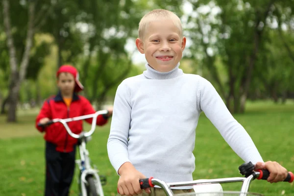 Menino em uma bicicleta no parque verde — Fotografia de Stock