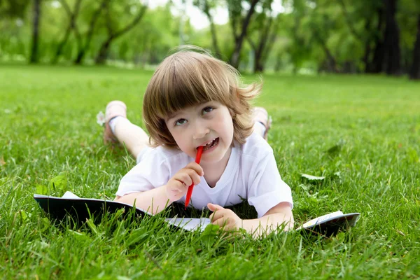 Porträt eines kleinen Mädchens, das im Park ein Buch liest — Stockfoto