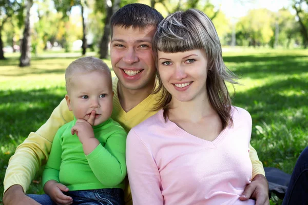 Família jovem com uma criança no parque de verão — Fotografia de Stock