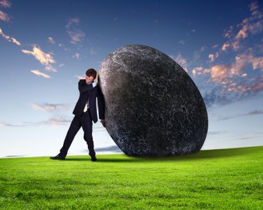 Businessman rolling a giant stone clipart