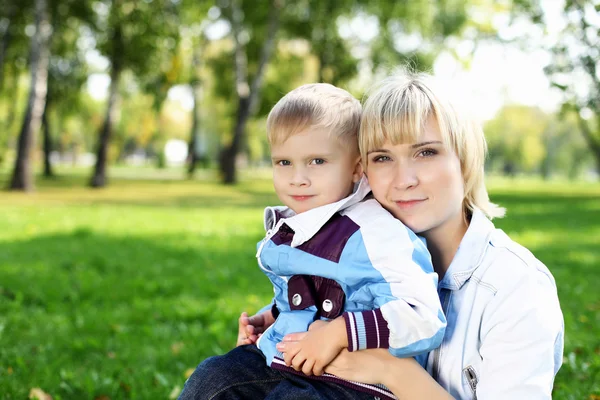 Młoda matka z synem w lato park — Zdjęcie stockowe