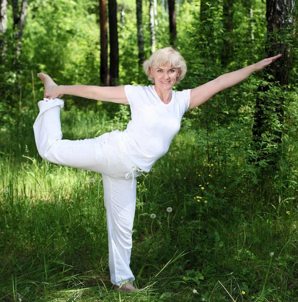 An elderly woman practices yoga — Stock Photo, Image