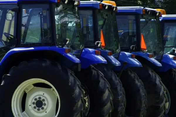 Aufstellung blauer Traktoren auf einem Feld — Stockfoto
