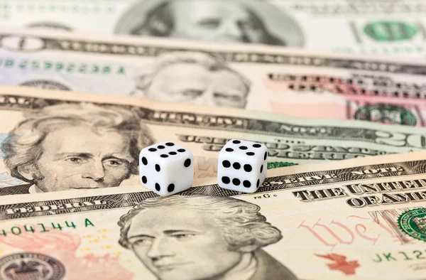 Two dice laying over a pile of money — Stock Photo, Image