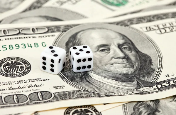 Two dice laying over a pile of money — Stock Photo, Image