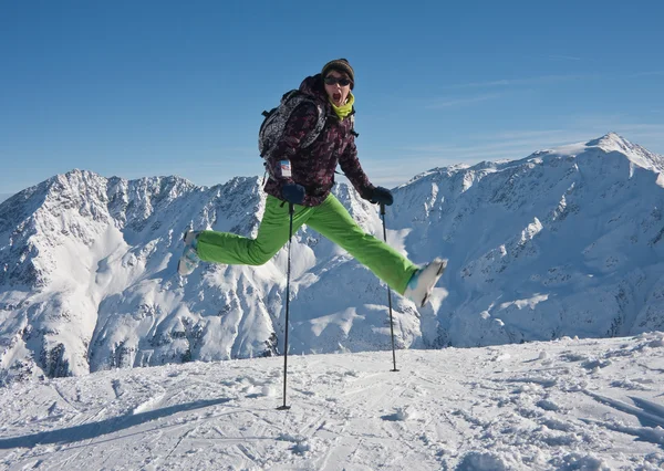 Mulher em panos de esqui saltando sobre as montanhas nevadas, Áustria — Fotografia de Stock