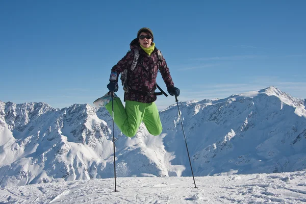 Mulher em panos de esqui saltando sobre as montanhas nevadas, Áustria — Fotografia de Stock