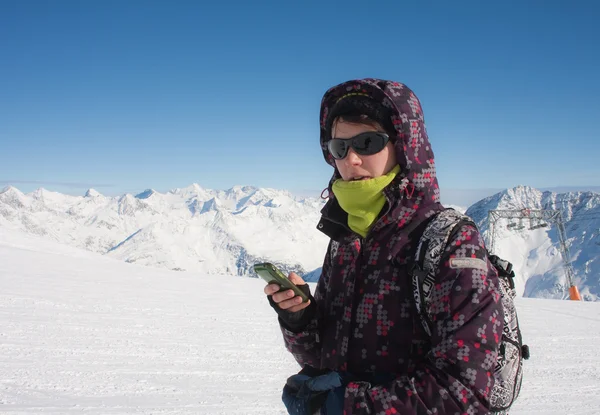 Лыжник в горах с мобильным телефоном в руке — стоковое фото