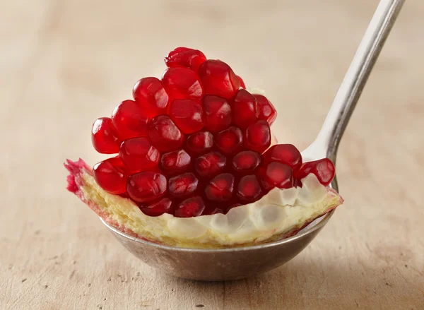 Pomegranate seeds in silver spoon — Stock Photo, Image