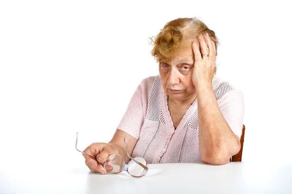 Удумлива бабуся сидить за столом ізольовано — стокове фото