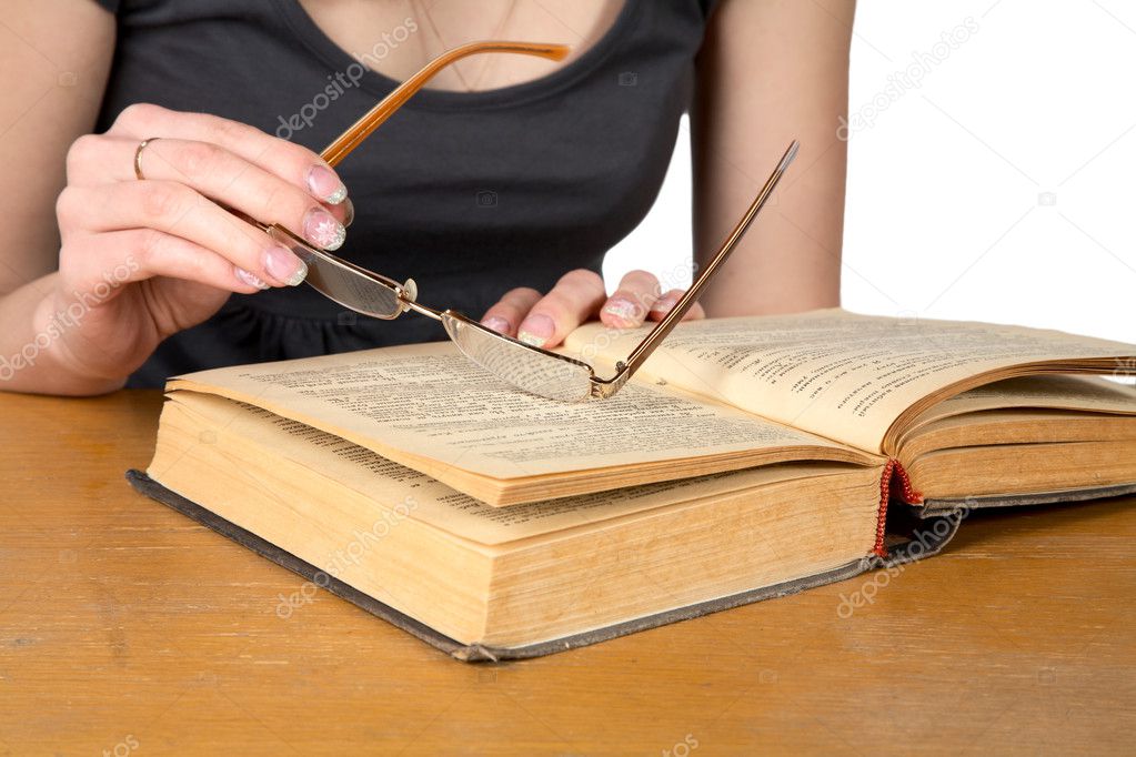 Hands of girl with glasses over the opened book isolated