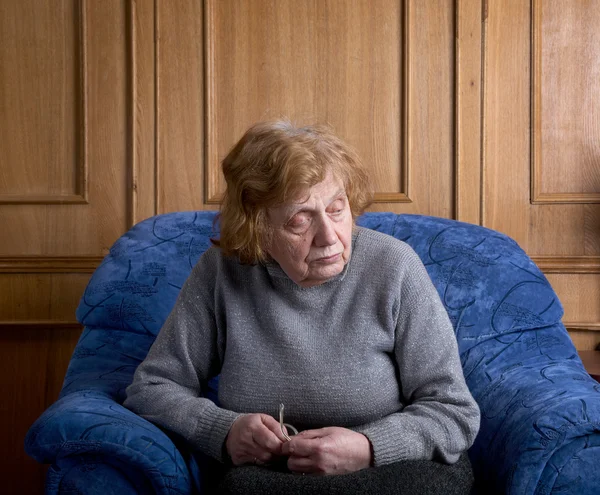 Η ηλικιωμένη γυναίκα που κάθεται σε μια πολυθρόνα — Φωτογραφία Αρχείου