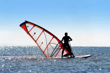 Windsurfer picks up the sail clipart