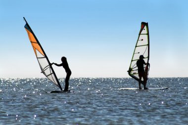 Silhouette of a two windsurfers clipart