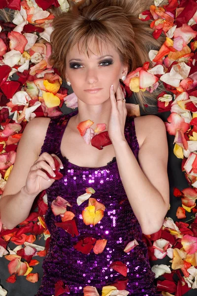 Young blonde lying in rose petals — Stock Photo, Image