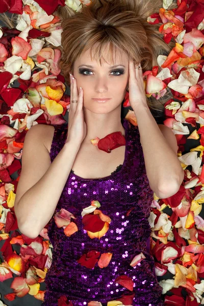 Молодая блондинка лежит в лепестках роз — стоковое фото