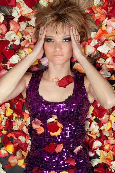 Lovely young blonde lying in rose petals — Stock Photo, Image