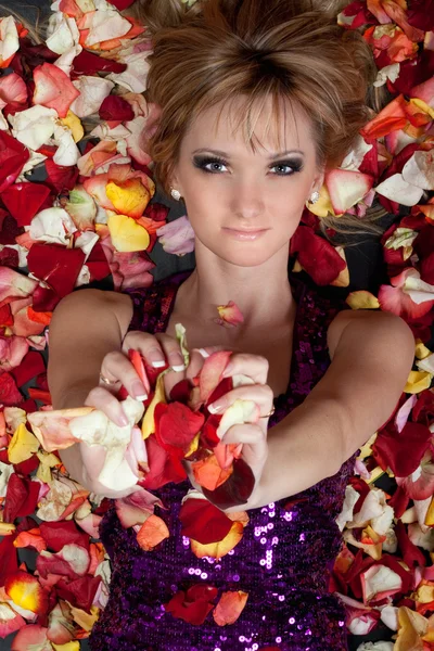 魅力的な若いブロンド薔薇の花びらで横になっています。 — ストック写真