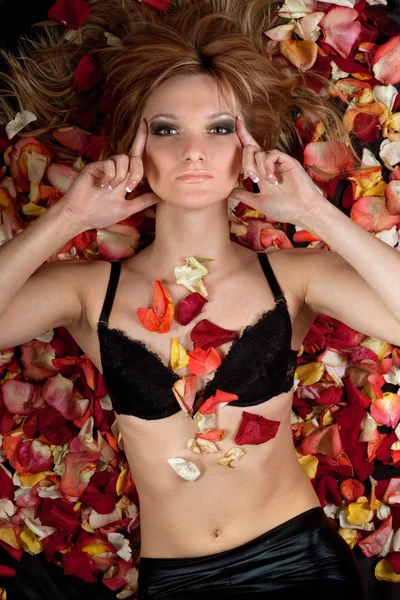 Чуттєва блондинка лежить в пелюстках троянд — стокове фото