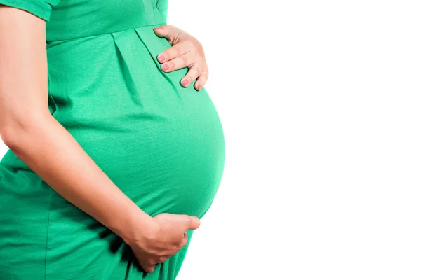 Живот беременной девушки в зеленом платье — стоковое фото