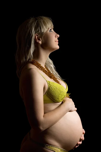 Gelukkig zwangere jonge vrouw in gele lingerie. geïsoleerd — Stockfoto