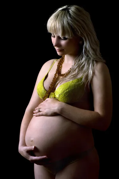 黄色のランジェリーで若い妊娠中の女性。分離されました。 — ストック写真