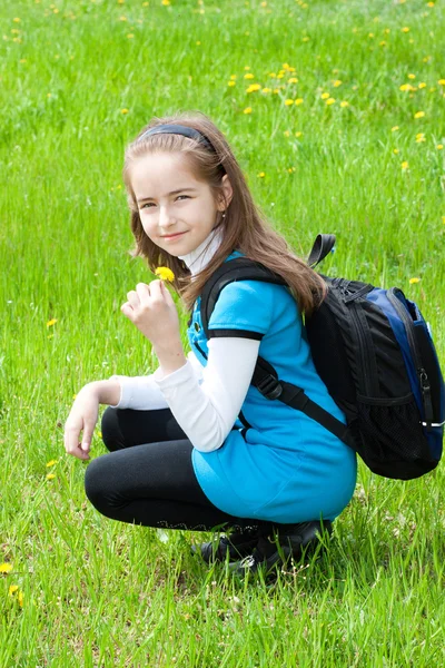 Schoolgirl against a green grass — Stock Photo, Image