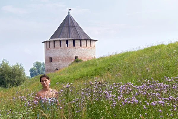Vrouw in veld op kasteel achtergrond — Stockfoto