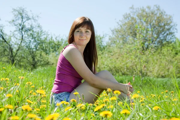 Menina sentada no prado do dente-de-leão — Fotografia de Stock