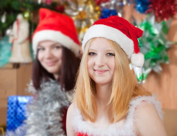 Meisjes in santa hoeden in kerstavond — Stockfoto