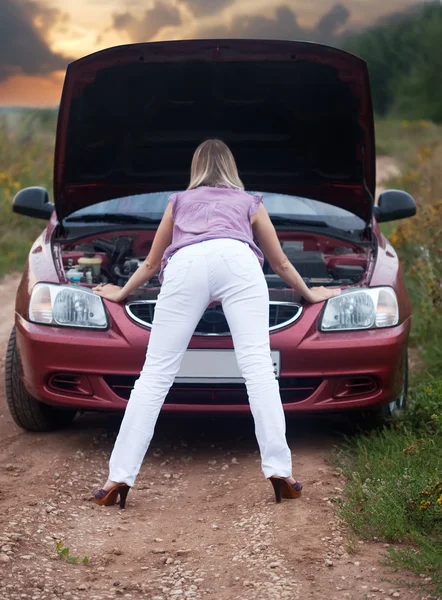 Σέξι κορίτσι ψάχνει κάτω από την κουκούλα αυτοκινήτων — Φωτογραφία Αρχείου