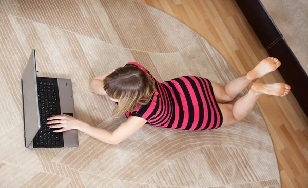 Chica acostada en el suelo y el uso de ordenador portátil —  Fotos de Stock