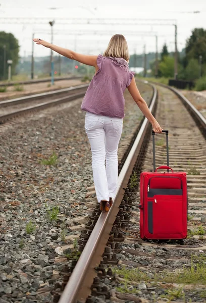 Žena se zavazadly na železniciレールの上を歩いて荷物を持つ女性 — Stock fotografie