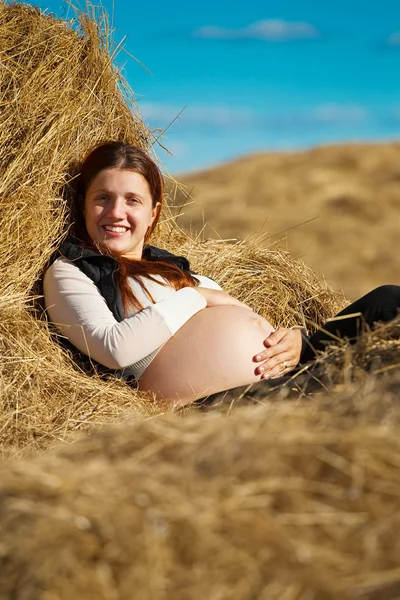 Pregnant girl resting on hay Stock Photo