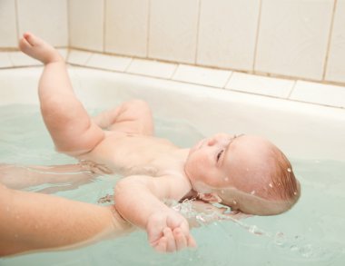 Baby swimming on mother's hands clipart