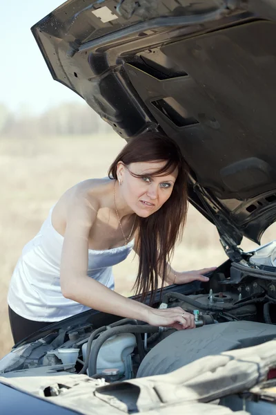 Vrouw op zoek onder auto motorkap — Stockfoto