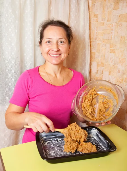 Woman puts dough into roasting pan — Stock Photo, Image