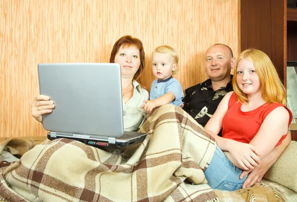 ラップトップとソファの上の家族 — ストック写真
