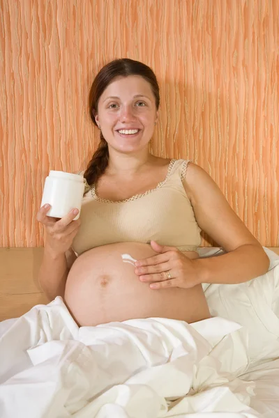 Mulher grávida esfrega creme — Fotografia de Stock