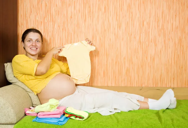 Mulher grávida com roupas de bebê — Fotografia de Stock