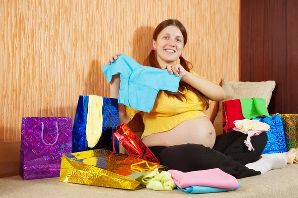 Bebek giysileri ile hamile kadın — Stok fotoğraf