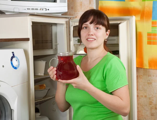냉장고에 과일 음료와 함께 용기를 퍼 팅 하는 여자 — 스톡 사진