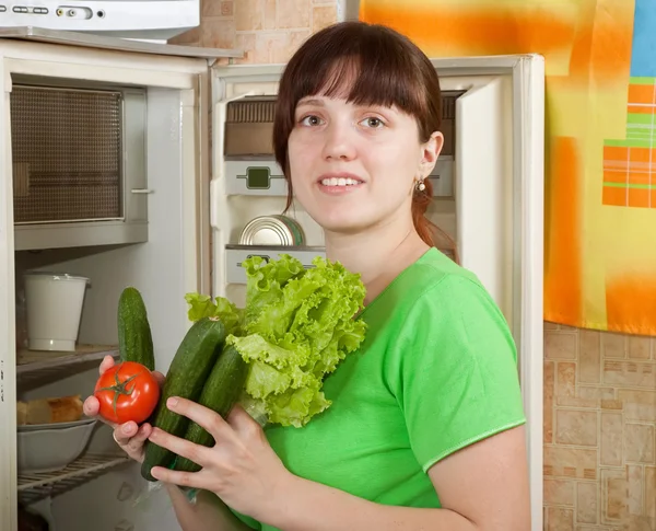 Mujer poniendo verduras frescas en la nevera — Foto de Stock